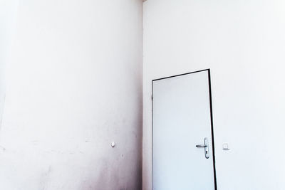 Low angle view of closed white door on wall