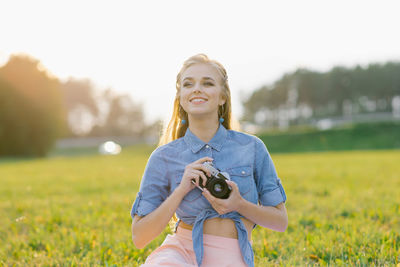 Student girl holds a camera in her hands in the summer outdoors