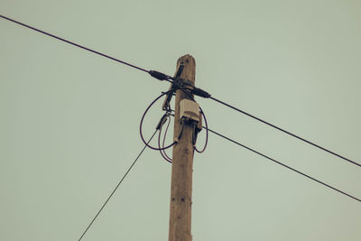 Low angle view of electricity pylon against clear sky