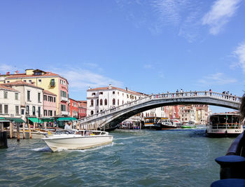 Bridge over canal by buildings against sky in city