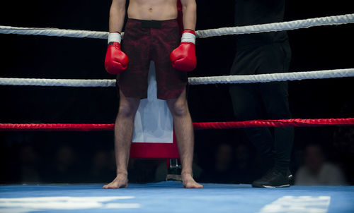 Low section of shirtless boxer standing in boxing ring