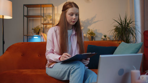 Portrait of young woman using laptop at home