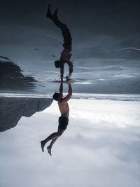 Upside down image of man doing handstand at beach