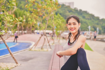 Happy young woman exercising on promenade at park