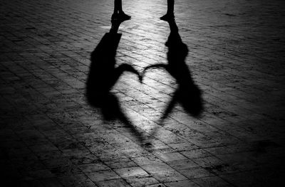 Low section of silhouette man standing on heart shape