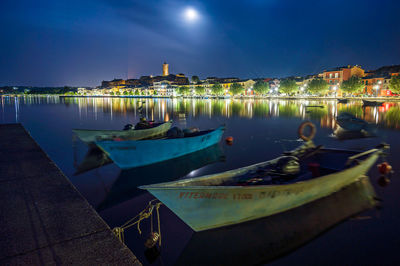 Boats moored in lake against sky at night