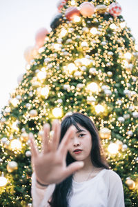 Portrait of beautiful woman standing against tree