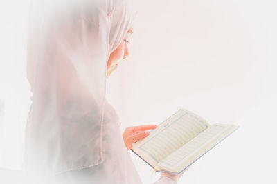 Midsection of woman reading book against white background