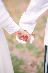 Midsection of bride and groom holding hands