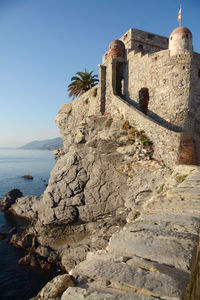 Old building by sea against clear sky