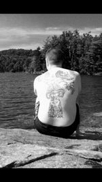 Rear view of a man sitting by lake