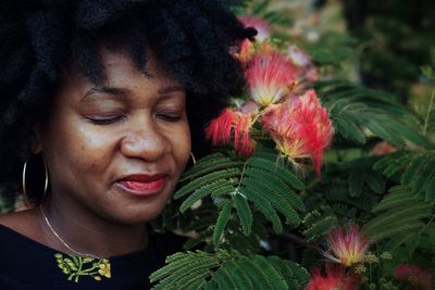 Close-up of mature woman with eyes closed by pink flowers