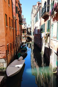 Boats moored in canal amidst buildings in city