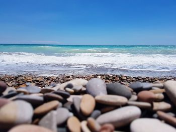 Pebbles on beach against clear blue sky