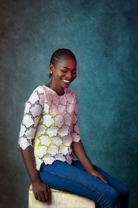 Portrait of a smiling girl sitting against wall