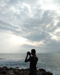 Man photographing sea against sky