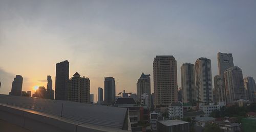 Modern buildings in city against sky during sunset