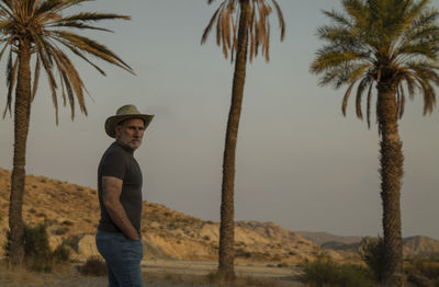 Adult man in cowboy hat in desert with palm trees. almeria, spain