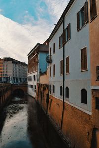 Bridge over canal amidst buildings against sky in city