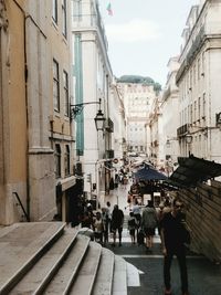 People walking on street amidst buildings in city