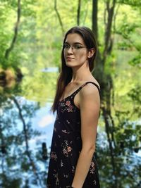 Portrait of beautiful young woman standing at lake