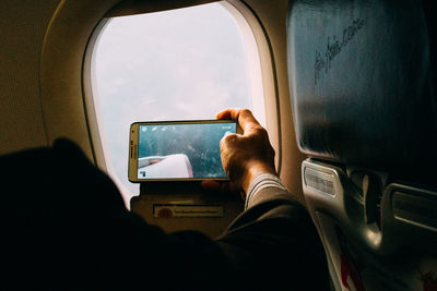 Reflection of man on window of airplane