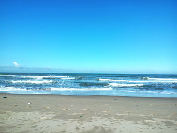 Scenic view of beach against clear blue sky