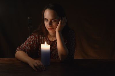 Portrait of woman with candle on table