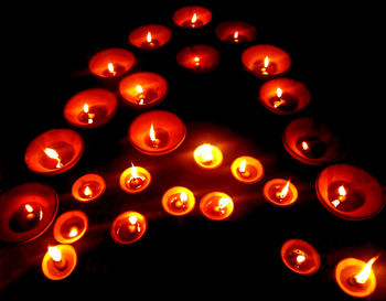Low angle view of illuminated candles against black background