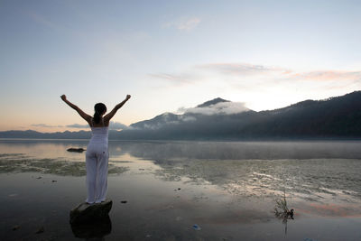 Rear view of woman on lake against sky