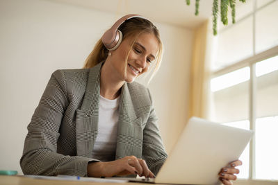 Young woman working at home with laptop on desk and headphones.  notebook for working. 