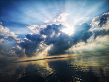 Sunlight streaming through clouds over sea