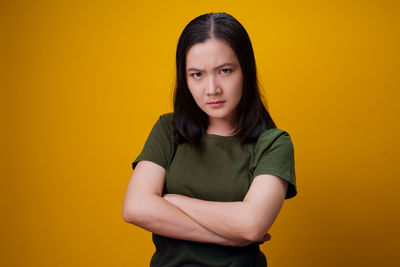 Portrait of beautiful young woman against yellow background