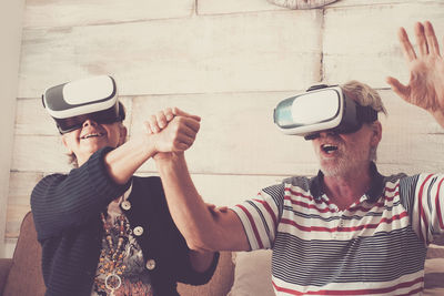 Senior couple looking through virtual reality simulator while sitting on sofa at home