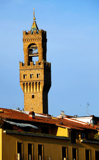 Low angle view of palazzo vecchio by residential building in tuscany against sky