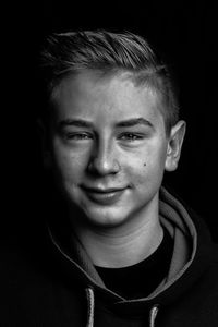 Portrait of young woman against black background