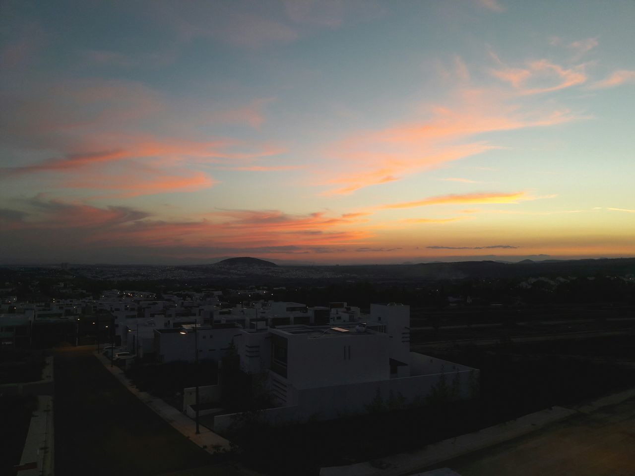 building exterior, cityscape, architecture, sunset, built structure, city, high angle view, crowded, sky, residential district, orange color, residential building, residential structure, cloud - sky, dusk, aerial view, city life, outdoors, no people, house