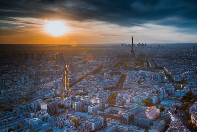 Eiffel tower with cityscape against cloudy sky during sunset