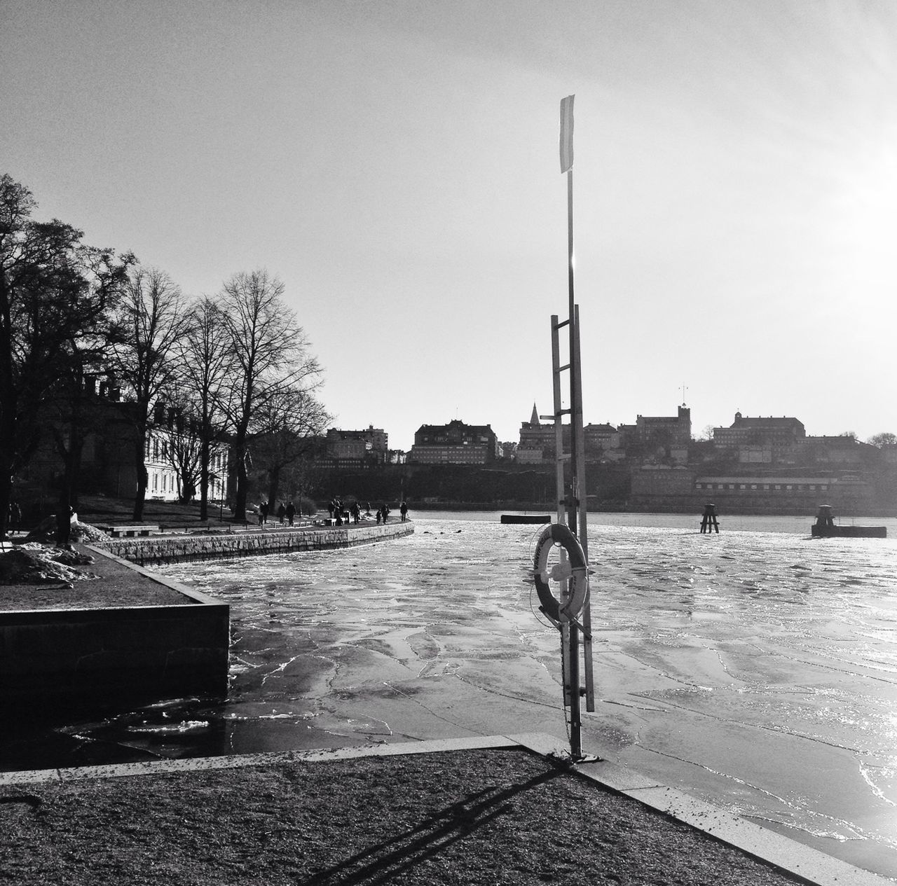 water, clear sky, tree, sunlight, sky, building exterior, sea, city, street light, built structure, day, nature, outdoors, incidental people, architecture, beach, river, fountain, shadow, tranquility