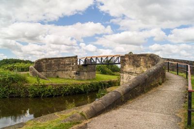 Bridge over river against cloudy sky