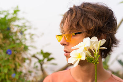 Close-up portrait of woman holding red flowering plant