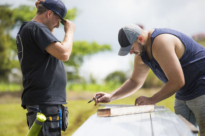 Two men measuring brackets for solar panel installation.