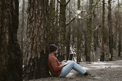 Rear view of woman sitting in forest