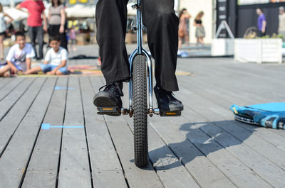 Low section of man riding unicycle on hardwood floor