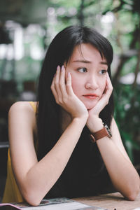 Thoughtful woman with hands on chin sitting at cage