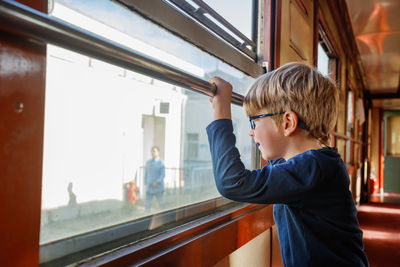 Side view of boy looking through window