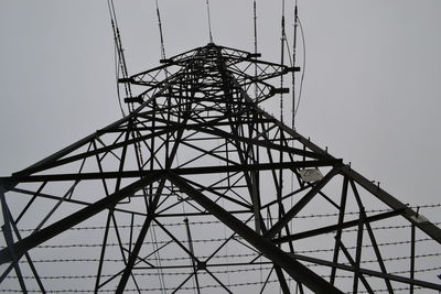 Low angle view of electricity pylon against clear sky