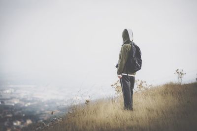 Side view of hiker standing on hill against clear sky