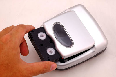 Cropped hand of person putting audio cassette in personal stereo