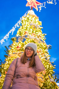 Portrait of young woman standing against blue sky